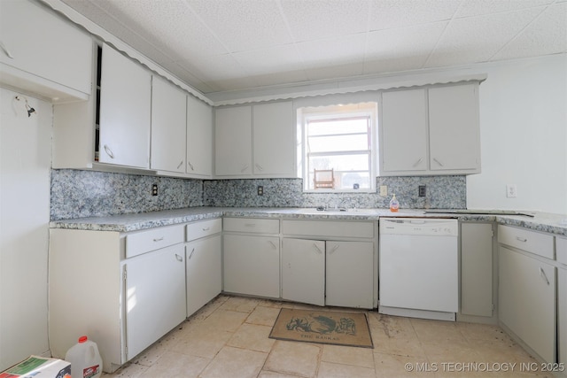 kitchen featuring a sink, backsplash, light countertops, and white dishwasher