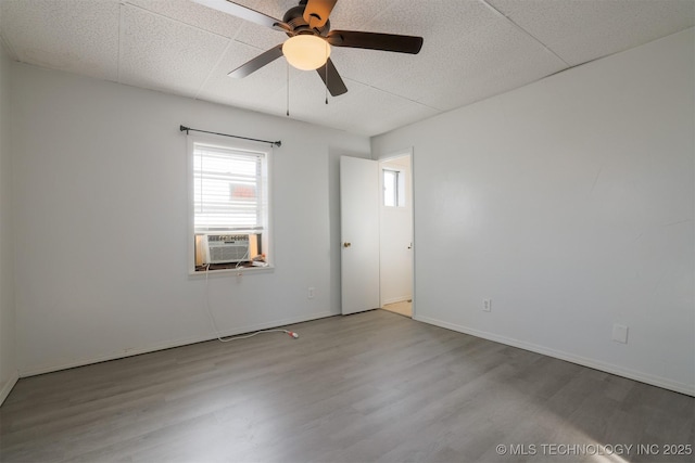 unfurnished room with cooling unit, baseboards, wood finished floors, and a ceiling fan