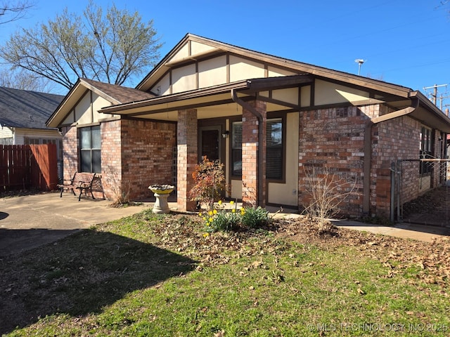 view of front of property with stucco siding, a patio, brick siding, and fence