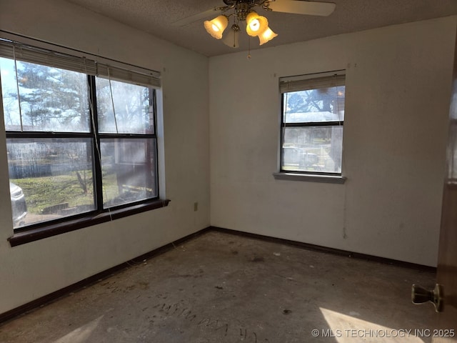 unfurnished room with baseboards, a textured ceiling, concrete flooring, and a ceiling fan