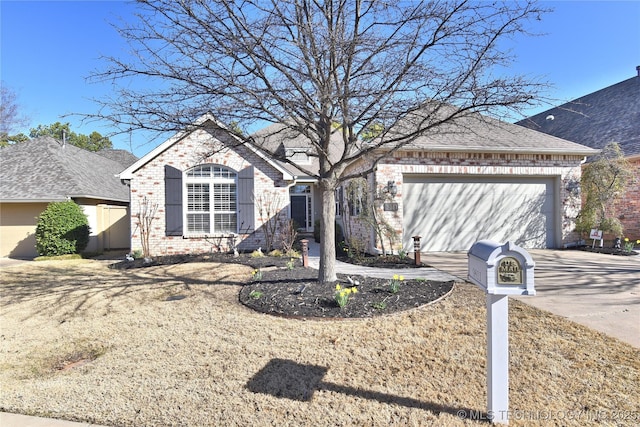 french country style house featuring brick siding, driveway, an attached garage, and roof with shingles