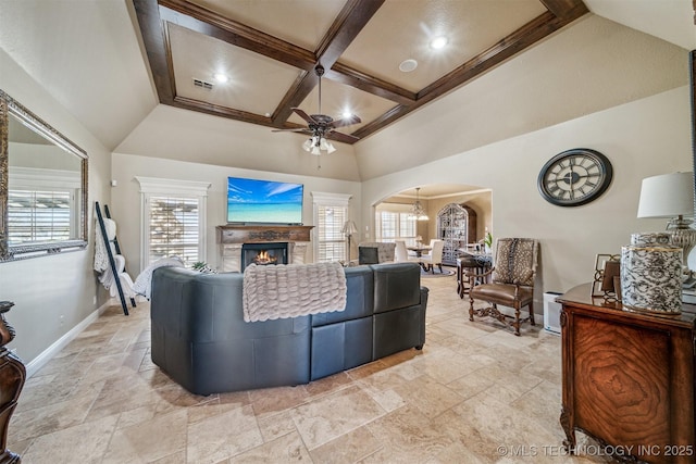 living room featuring coffered ceiling, arched walkways, baseboards, a healthy amount of sunlight, and ceiling fan