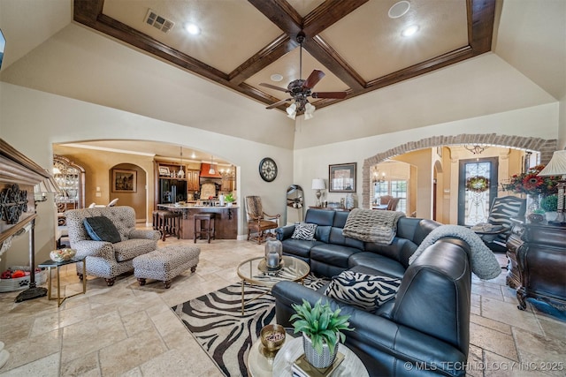 living area with visible vents, coffered ceiling, stone tile floors, arched walkways, and a high ceiling