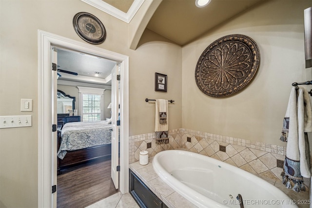 ensuite bathroom featuring tile patterned floors, crown molding, a tray ceiling, ensuite bathroom, and a bath