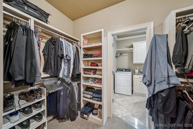 walk in closet with washer / clothes dryer and light colored carpet