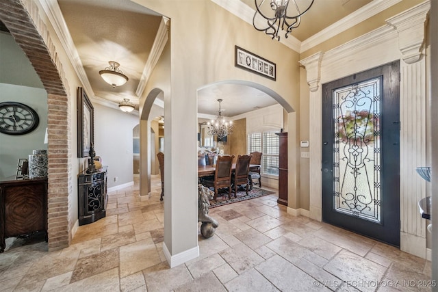 entryway featuring stone tile flooring, a chandelier, arched walkways, and baseboards