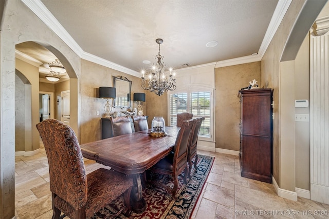 dining area featuring baseboards, a chandelier, ornamental molding, arched walkways, and stone tile flooring