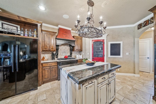 kitchen with black fridge, custom range hood, a kitchen island, stone tile floors, and arched walkways