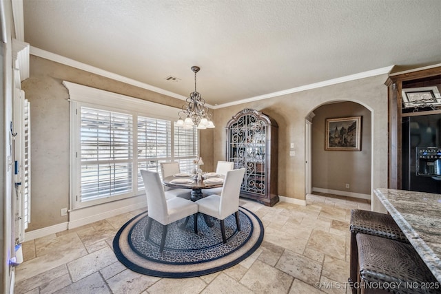 dining area featuring stone tile flooring, an inviting chandelier, crown molding, and baseboards