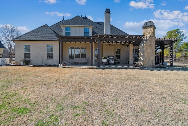 back of house featuring a lawn, a pergola, fence, a chimney, and a patio area