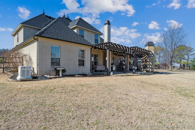 back of house with a yard, a pergola, a chimney, a patio area, and brick siding