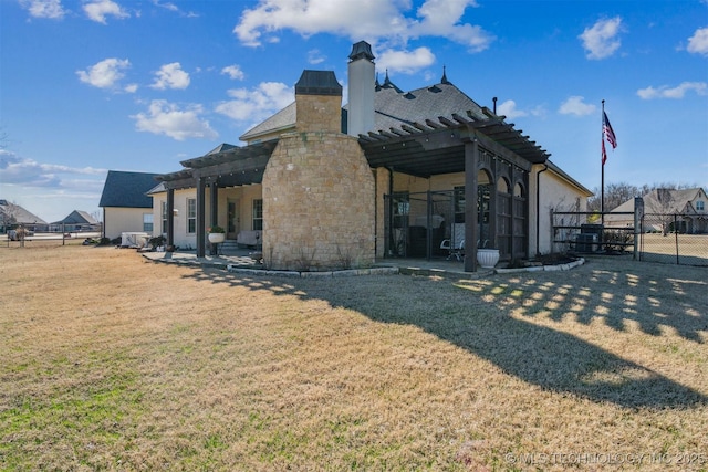 back of property with fence, a yard, a pergola, stone siding, and a patio area