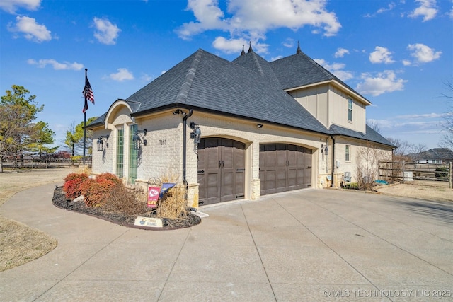 view of side of property featuring driveway, fence, roof with shingles, a garage, and brick siding