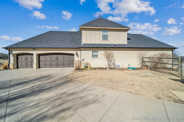 exterior space with board and batten siding, fence, concrete driveway, central AC, and a garage