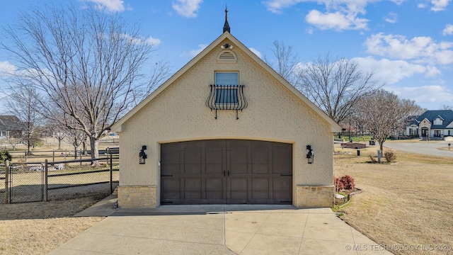 garage featuring concrete driveway and fence