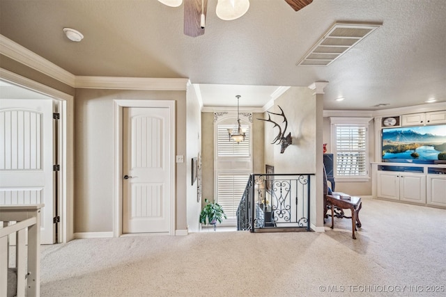 hallway with an upstairs landing, visible vents, ornamental molding, and carpet floors