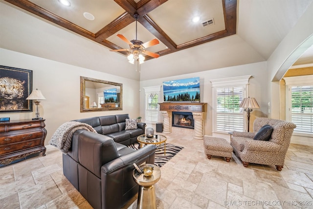 7161 Hackberry Rdg, Owasso, OK 74055 - living room featuring stone tile floors, coffered ceiling, ceiling fan, a fireplace with flush hearth, and arched walkways