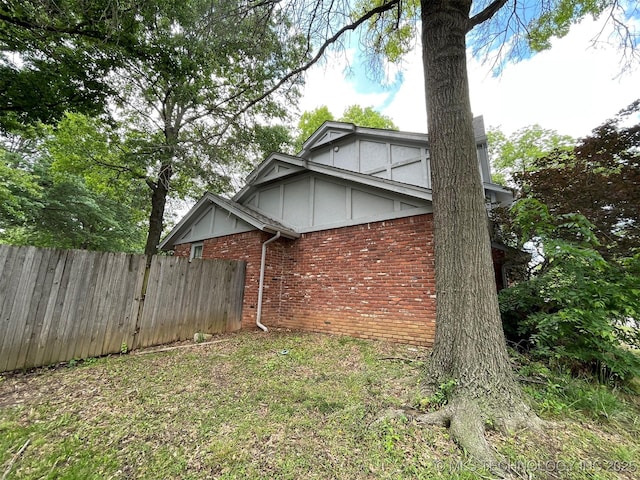 view of home's exterior featuring board and batten siding, fence, and brick siding