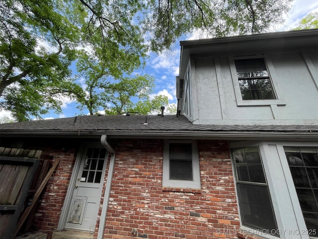 exterior space featuring brick siding, stucco siding, and a shingled roof