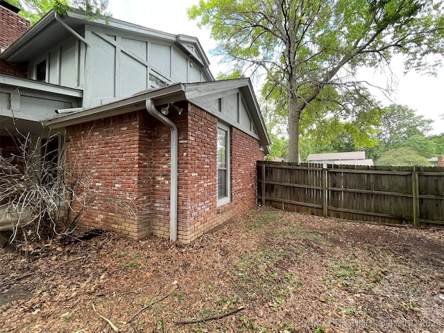 view of property exterior featuring brick siding and fence