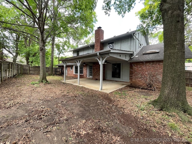 rear view of house featuring a fenced backyard, a shingled roof, a chimney, a patio area, and brick siding