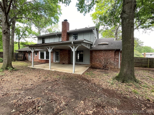 back of property with brick siding, a chimney, a patio, and fence