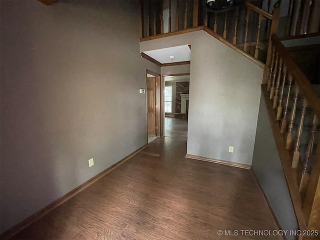 corridor with stairway, wood finished floors, and baseboards