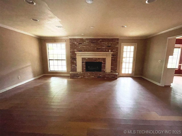 unfurnished living room with baseboards, a fireplace, wood finished floors, and crown molding