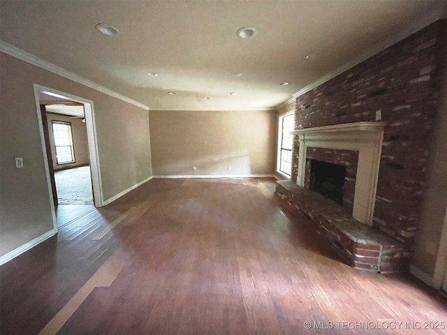 unfurnished living room featuring a brick fireplace, crown molding, baseboards, and wood finished floors