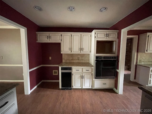 kitchen featuring black oven, recessed lighting, light wood-style floors, decorative backsplash, and baseboards