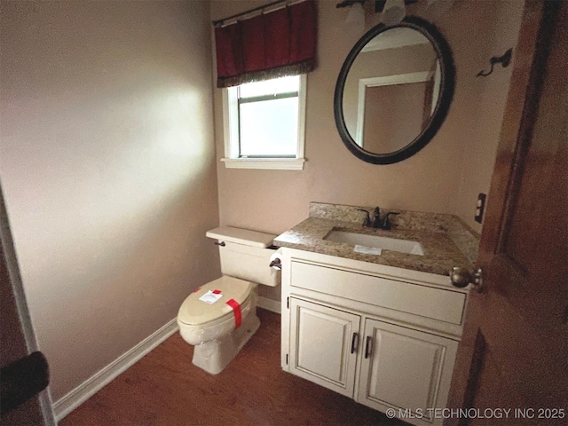 half bath featuring baseboards, toilet, and vanity