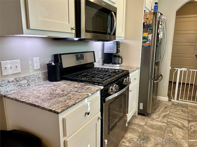 kitchen featuring light stone counters, appliances with stainless steel finishes, and white cabinetry