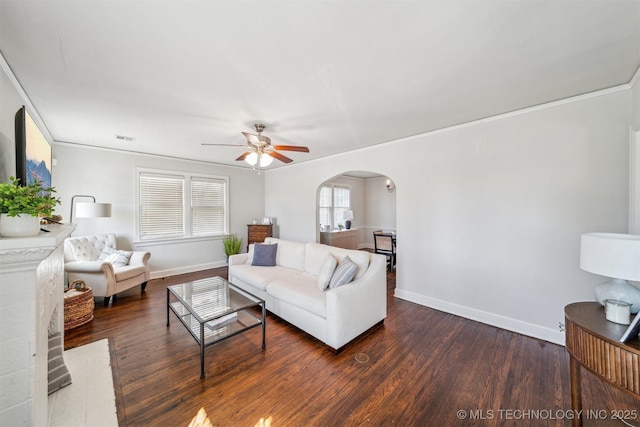 living room featuring arched walkways, visible vents, baseboards, and wood finished floors