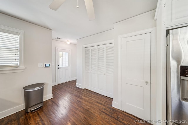 interior space featuring visible vents, baseboards, a ceiling fan, and dark wood-style flooring