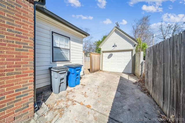 detached garage featuring fence and driveway