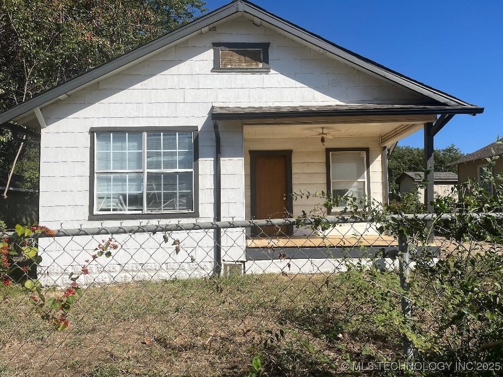 bungalow with a fenced front yard, roof with shingles, and covered porch