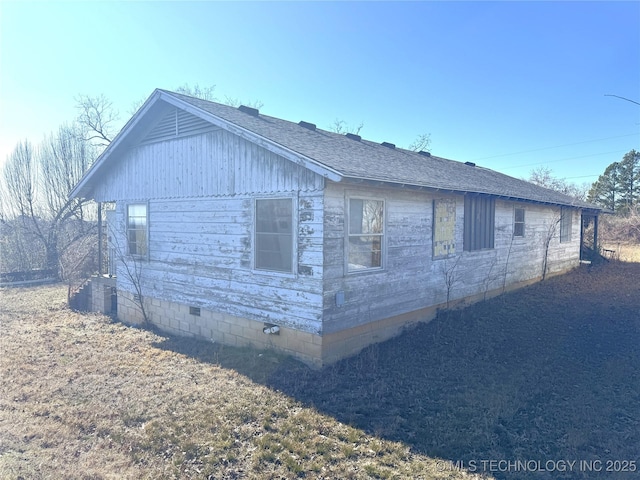 view of home's exterior featuring crawl space and roof with shingles