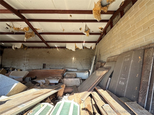 interior space with beam ceiling and brick wall