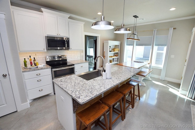 kitchen with a center island with sink, a sink, stainless steel appliances, white cabinets, and decorative backsplash