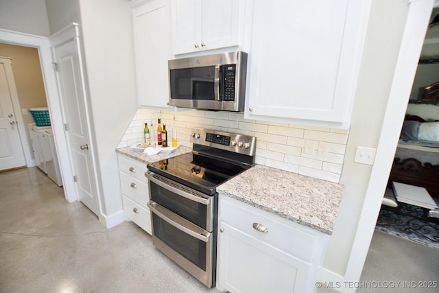 kitchen featuring white cabinetry, washing machine and dryer, backsplash, and stainless steel appliances