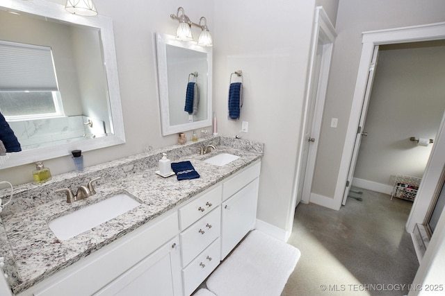 full bath with double vanity, finished concrete flooring, baseboards, and a sink