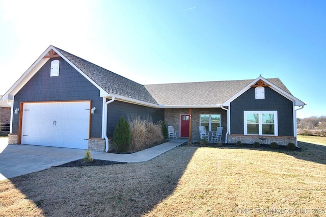 craftsman-style house featuring a front lawn, an attached garage, driveway, and roof with shingles