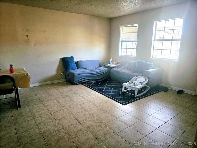 living area with tile patterned floors, baseboards, and a textured ceiling