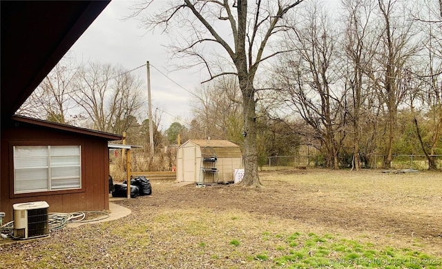 view of yard with a storage unit, a fenced backyard, central AC unit, and an outdoor structure