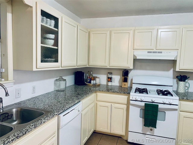 kitchen featuring under cabinet range hood, a sink, white appliances, tile patterned flooring, and glass insert cabinets