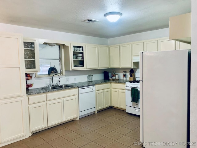 kitchen with visible vents, glass insert cabinets, white appliances, a textured ceiling, and a sink