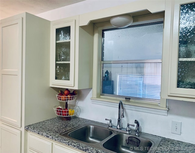 kitchen featuring white cabinets, glass insert cabinets, and a sink