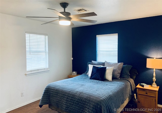 bedroom featuring visible vents, baseboards, wood finished floors, and a ceiling fan