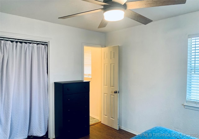 unfurnished bedroom featuring a ceiling fan, dark wood-type flooring, and baseboards