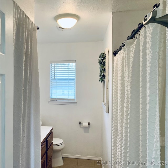 full bath with vanity, baseboards, tile patterned flooring, a textured ceiling, and toilet